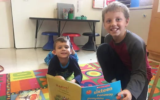 a person and a boy sitting at a table with a box