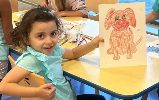a child sitting at a table with a stuffed animal