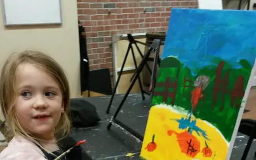a girl standing next to a painting