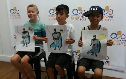 a group of boys holding up drawings