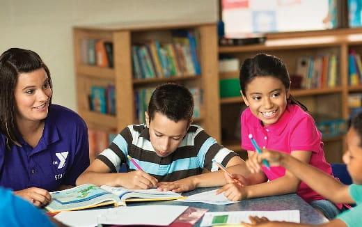 a group of children sitting at a table in a library