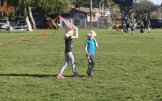 a couple of kids playing with a kite in a park