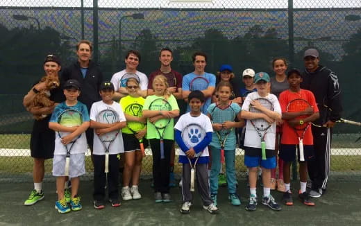 a group of people posing for a photo on a tennis court