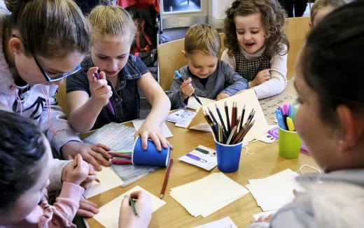 a group of children sitting at a table writing on paper