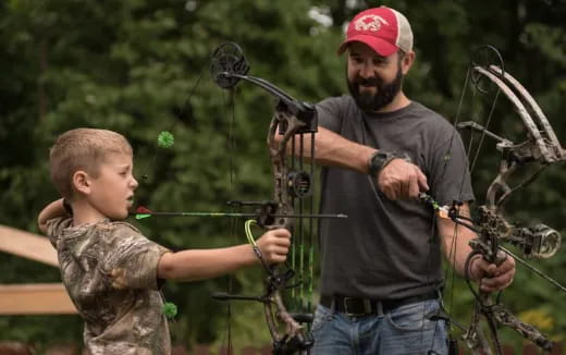 a person and a boy holding a bow and arrow