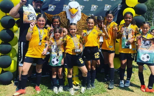 a group of girls in yellow shirts holding balloons