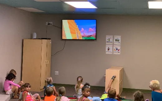 a group of children sitting in a classroom watching a presentation