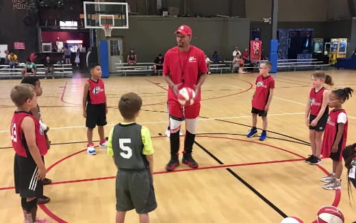 a person standing in front of a group of kids playing volleyball