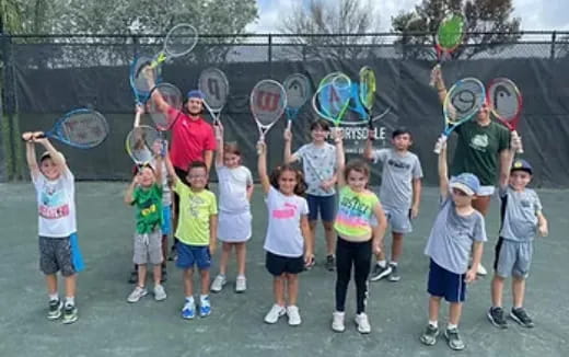 a group of kids holding tennis rackets
