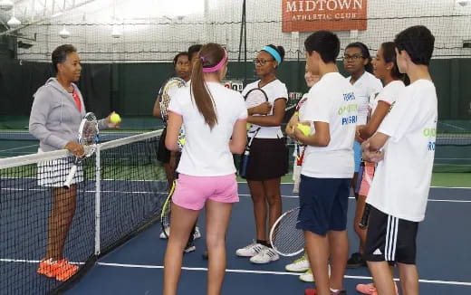 a group of people stand on a tennis court