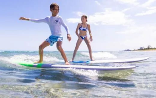 a boy and girl on a surfboard in the water