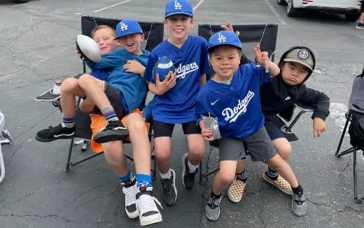 a group of boys sitting on a bench holding baseballs