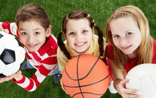a group of children holding football balls