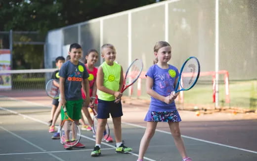 a group of kids holding tennis rackets