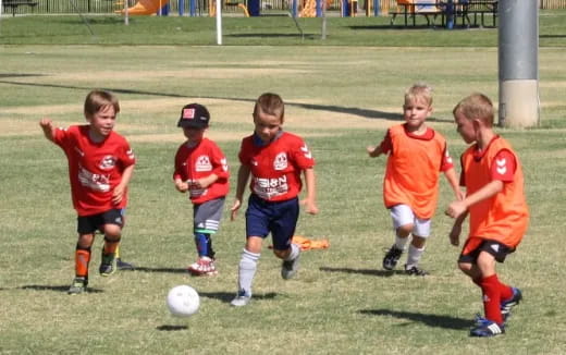 a group of kids compete over a football ball