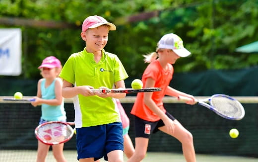 a group of kids playing tennis