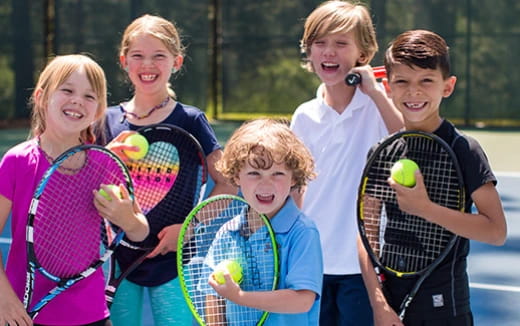 a group of kids holding tennis rackets