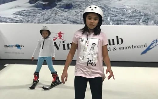 a couple of kids wearing helmets and ice skates