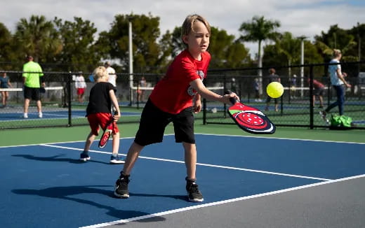 a boy hitting a ball with a tennis racket
