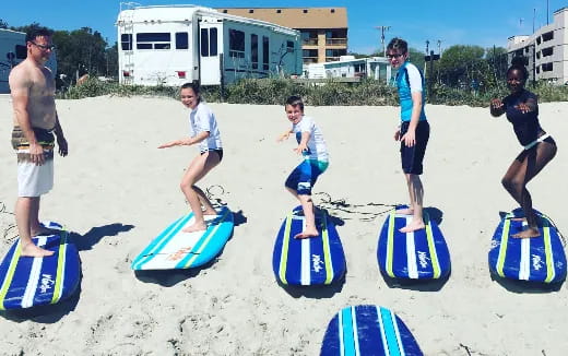 a group of people stand on surfboards on a beach