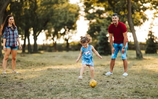 a man and a woman playing with a child in a park