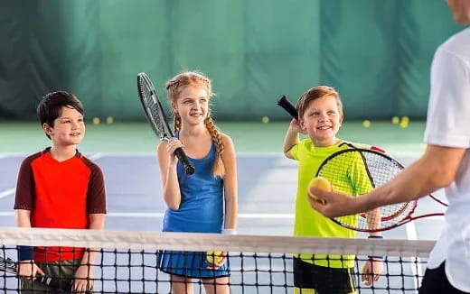 a group of kids playing tennis