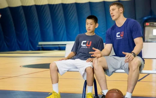 a couple of men sitting on a basketball court