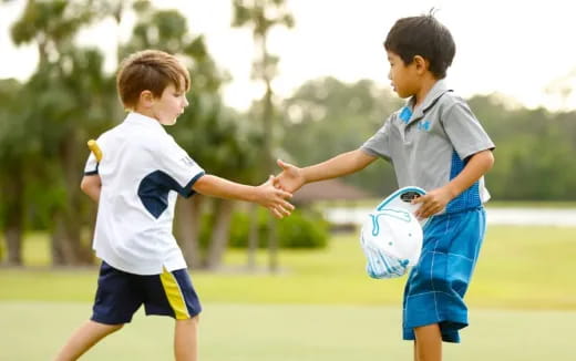 a couple of boys playing with a ball in a field