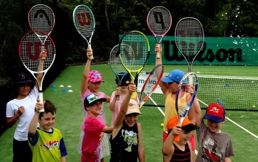 a group of kids holding tennis rackets