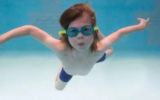 a woman wearing goggles and swimming underwater