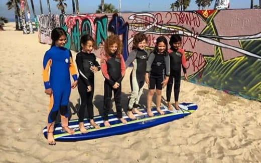 a group of kids standing on a surfboard