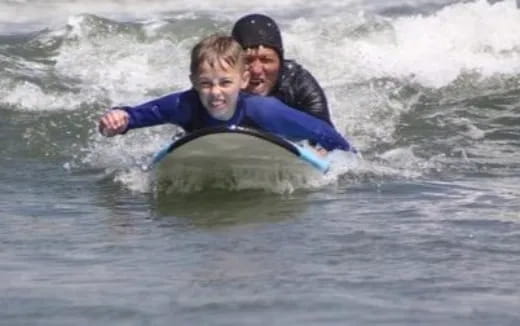 a person and a boy riding a surfboard