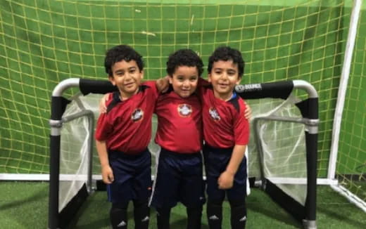 a group of boys posing for a picture in front of a football goal