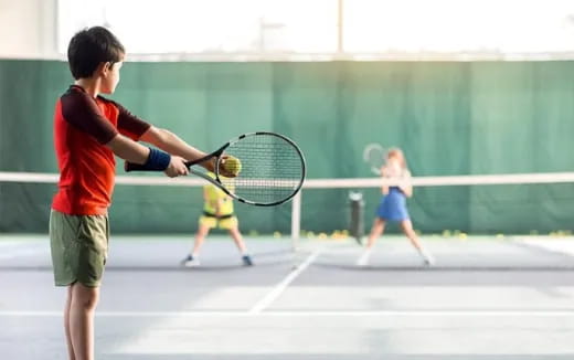 a boy hitting a ball with a tennis racket