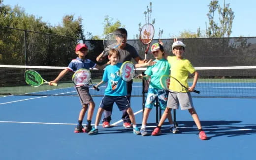 a group of kids holding tennis rackets