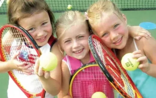 a group of kids holding tennis rackets