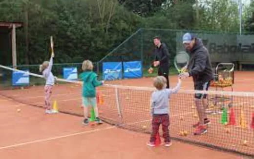 a group of kids playing tennis