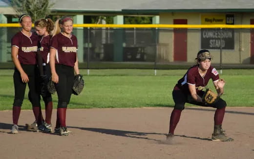 girls playing baseball on a field