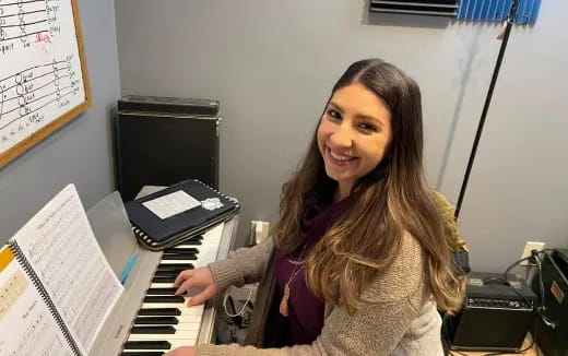 a woman smiling and playing a piano