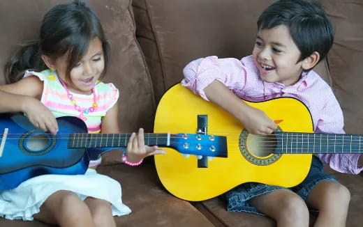 a couple of children playing a guitar