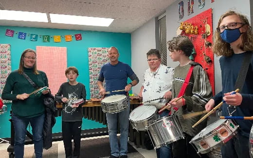 a group of people wearing masks and playing drums