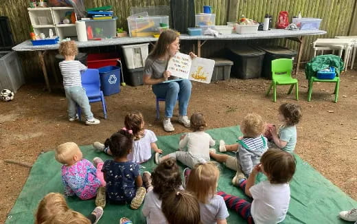 a person reading a book to a group of children