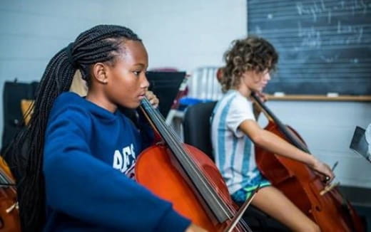 a person playing a violin next to a young girl