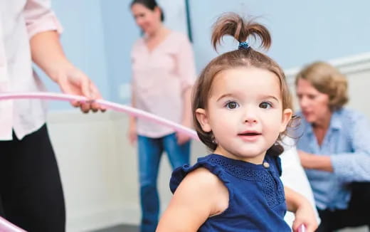 a young girl holding a pink ribbon