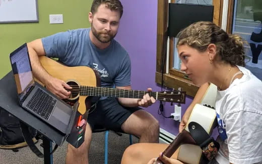 a man playing guitar next to a woman