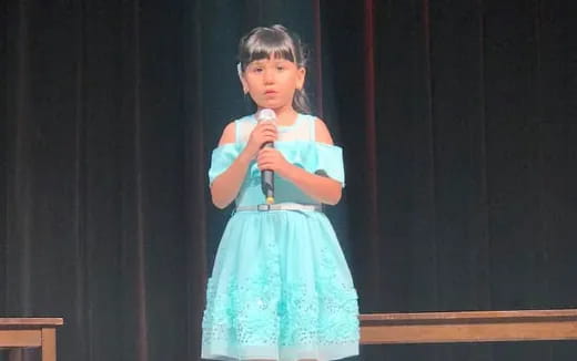 a girl in a blue dress holding a microphone