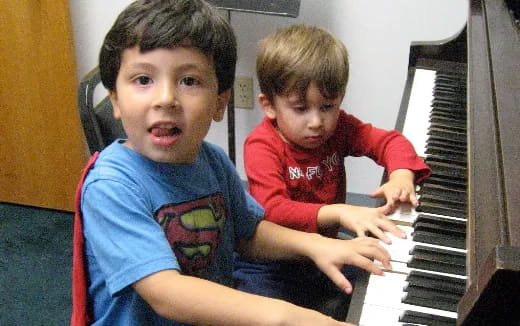 a couple of boys playing a piano