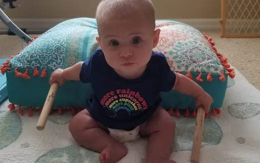 a baby sitting in a highchair holding a toy sword