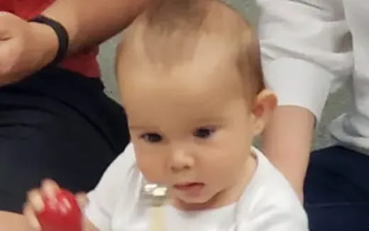 a baby with a person's hand on its head