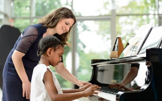 a woman and a child playing a piano